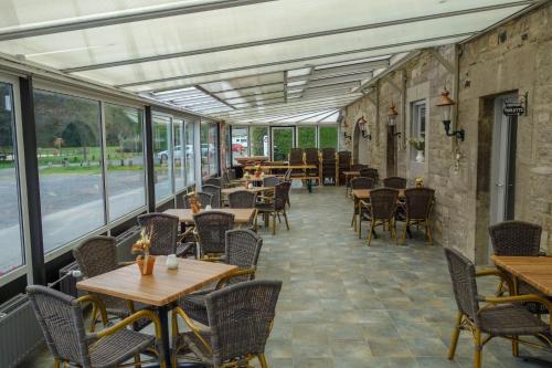 an empty restaurant with tables and chairs and windows at Camping Village Sy in Ferrières