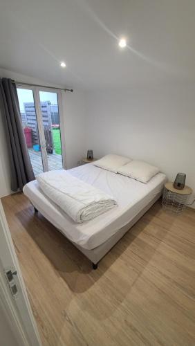 uma cama branca num quarto com uma grande janela em Petit séjour en chalet em Crecy la Chapelle