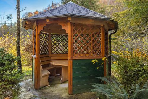 a wooden gazebo with a table in it at Cabin by the river Polhov Gradec in Polhov Gradec