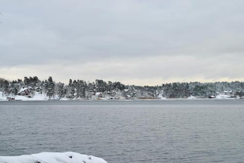 a snow covered lake with houses and trees at Sjöstuga/gästhus i skärgården. in Åkersberga