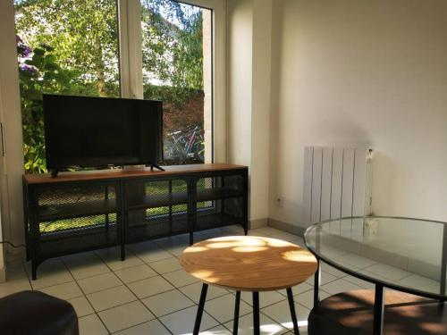 uma sala de estar com uma televisão e uma mesa de vidro em Maison au coeur de ville parking em Paimpol