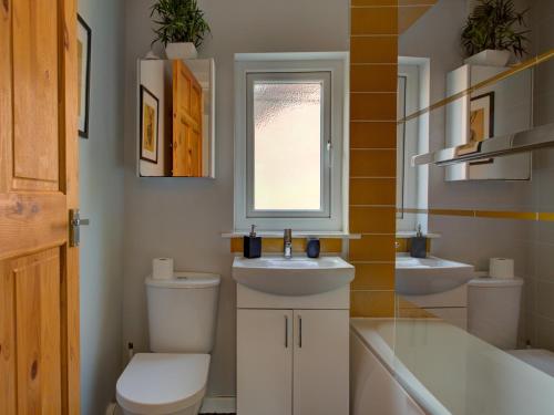 a bathroom with two sinks and a toilet and a window at Pass the Keys Colourful property sleeps 6 in Manchester