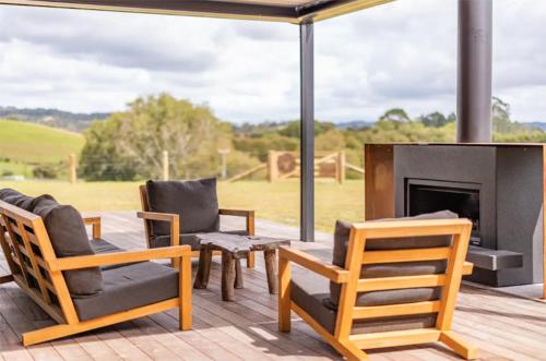 a group of chairs and a fireplace on a deck at Rusty Ram Luxury Lodge in Haruru