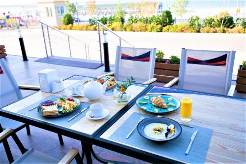 a table with plates of food on a balcony at MIRAMAR Apart Hotel & SPA in Aktau