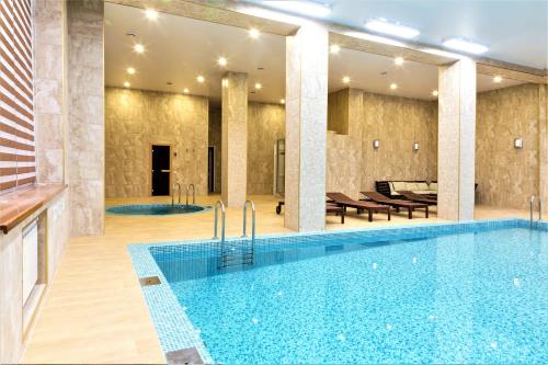 una piscina in un hotel con tavoli e sedie di MIRAMAR Apart Hotel & SPA ad Aqtau