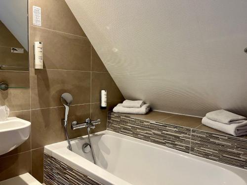 ein Badezimmer mit einer Badewanne, einem Waschbecken und Handtüchern in der Unterkunft Hôtel Morphée Lille Villeneuve d'Ascq in Villeneuve d'Ascq
