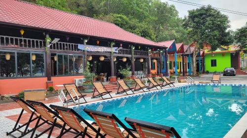 a pool with chairs in front of a building at Woodstock Beach Camp in Cat Ba