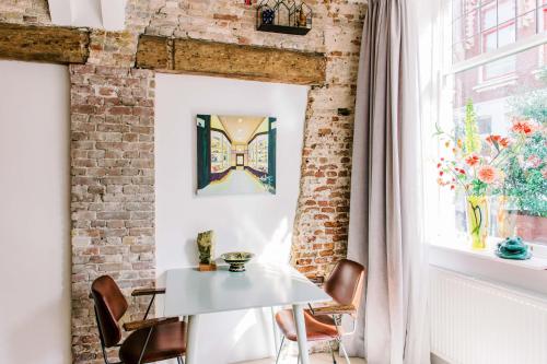 Habitación con una mesa y sillas blancas y una pared de ladrillo. en B&B À la Lon en Dordrecht
