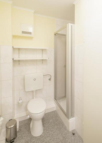 a white bathroom with a toilet and a shower at Marbijes Appartementhaus in Cuxhaven