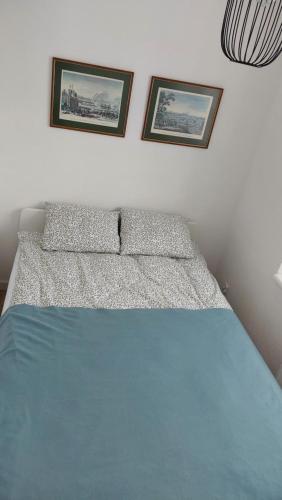 a bed in a bedroom with two pictures on the wall at Apartament z Napoleonem w tle in Lidzbark Warmiński