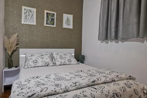 Cama blanca con edredón y almohadas blancos y negros en Apartman Liburna, en Rijeka