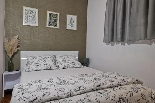 een wit bed met een zwart-wit dekbed en kussens bij Apartman Liburna in Rijeka
