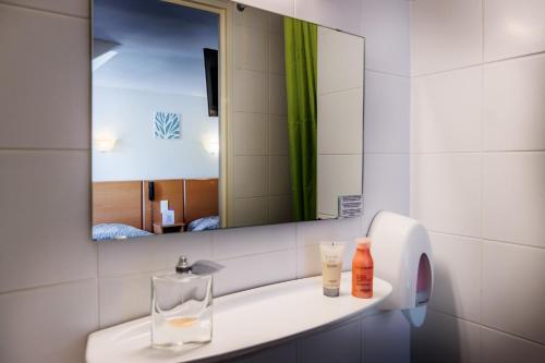 a bathroom with a sink with a mirror and a bottle at Hôtel Compostelle in Lourdes