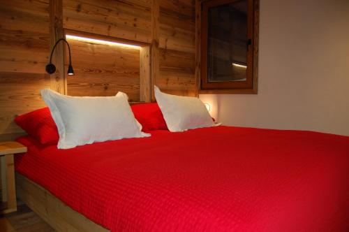 a bedroom with a red bed with white pillows at BnB Le Mazot Fionnay in Fionnay