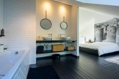 a bathroom with two sinks and a bed and a tub at La Maison Noire in La Roche-en-Ardenne