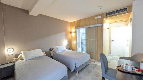 オルタ・サン・ジューリオにあるhotel garni Santa Caterinaのベッド2台、テーブル、椅子が備わる客室です。