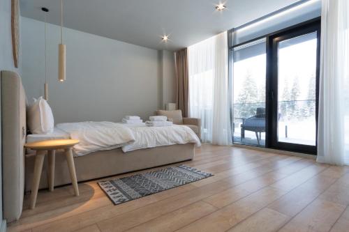 a bedroom with a bed and a table and a large window at SAVOIE Apartments Bukovel in Bukovel