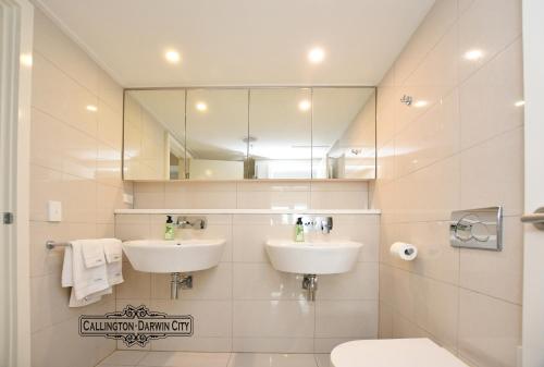 een badkamer met 2 wastafels en een spiegel bij “CALLINGTON” Darwin City @PenthousePads in Darwin