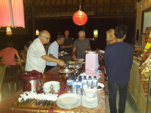 a group of people standing around a table in a restaurant at Beten Waru Bungalow and Restaurant in Amed