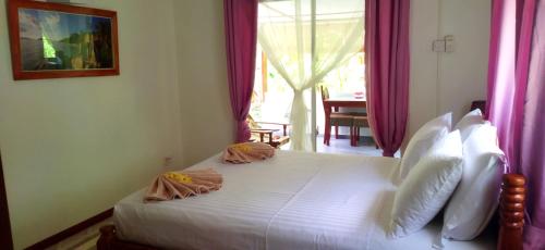 a bedroom with a large white bed with pink curtains at Dan Zoranz Self Catering Guest House in La Digue