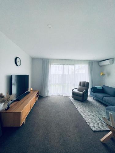 a living room with a television and a couch at Stylish Industrial Holiday House in Pakuranga Free Wifi Netflix in Auckland
