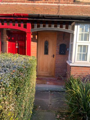 a red brick house with a wooden door at Knutsford Cottage in Knutsford