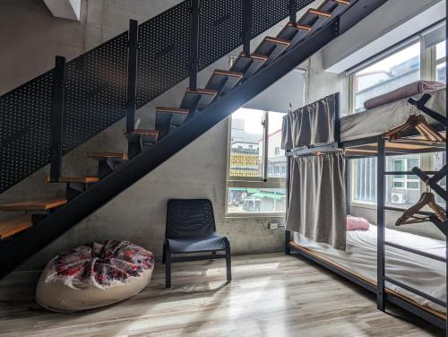a bedroom with bunk beds and a chair and a staircase at 40Inn Backpackers Warehouse in Taitung City
