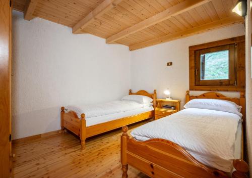 1 dormitorio con 2 camas y ventana en Baita Vioz, en Peio