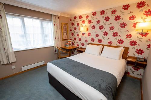 a hotel room with a bed and a flower wallpaper at Bridge Inn in Clevedon