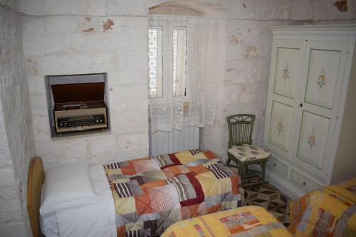 una camera con letto e TV a parete di trulli Annina a Locorotondo