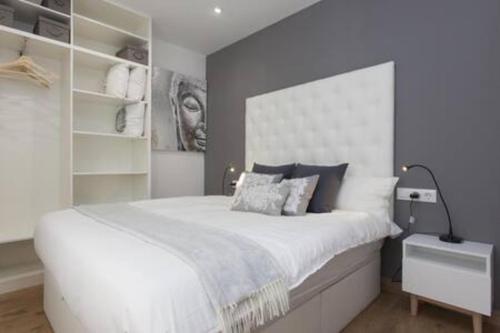 Un dormitorio con una gran cama blanca y estanterías en Designer Apt near FIRA Balcony 5PPWIFISMART TV by MyRentalHost, en Hospitalet de Llobregat