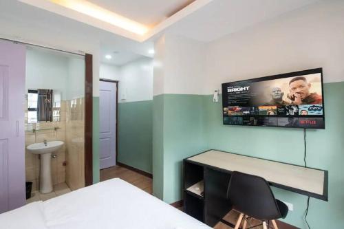 1 dormitorio con escritorio y TV en la pared en St. Marvin Studio Makati M503, en Manila