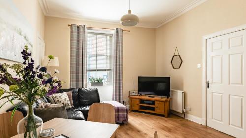 a living room with a couch and a tv at Sea Sound in Cellardyke