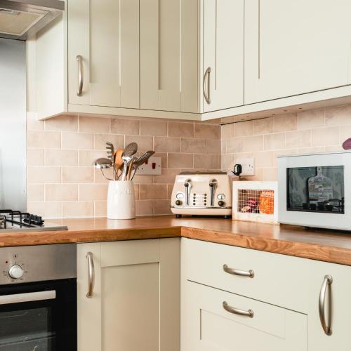 a kitchen with white cabinets and a microwave at Sea Sound in Cellardyke