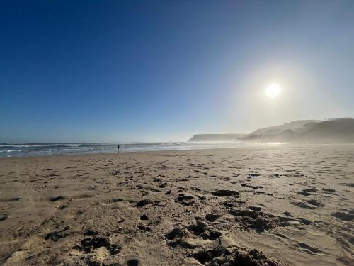 a person standing on a beach with the sun in the background at Mitford The N I C E Condo in Morganʼs Bay
