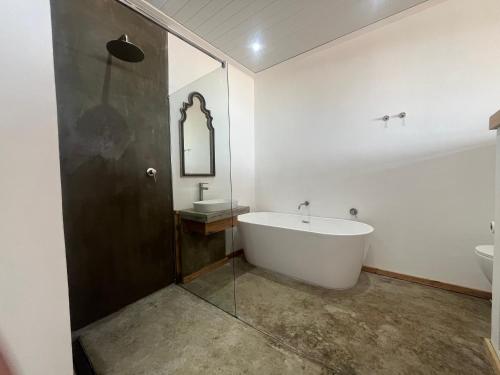 a bathroom with a bath tub and a sink at Mitford The N I C E Condo in Morganʼs Bay