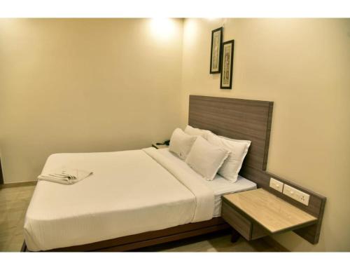 um quarto com uma cama branca e uma mesa em Hotel Dwarka, Nagpur em Nagpur
