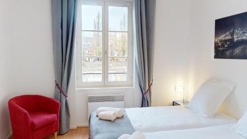 - une chambre avec une chaise rouge, un lit et une fenêtre dans l'établissement Au bord de l’eau, à Strasbourg