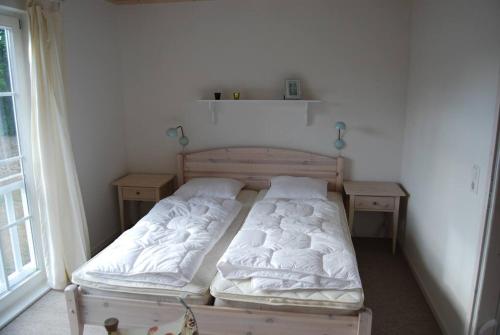 a bed in a room with two night stands and a window at Ferienhaus Meerblick in Sierksdorf