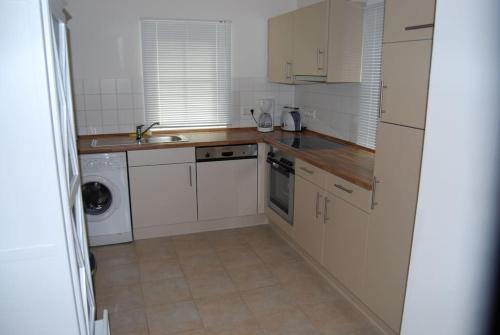 a kitchen with white cabinets and a sink and a dishwasher at Ferienhaus Meerblick in Sierksdorf