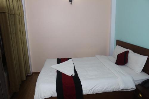 a bedroom with a bed with white sheets and pillows at Hotel Happy Home or Mudkhu Durbar in Kathmandu