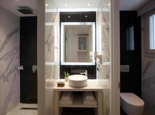 a bathroom with a sink and a toilet and a mirror at San Marco Hotel and Villas in Houlakia