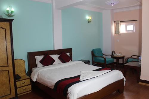 a bedroom with a bed and chairs in a room at Hotel Happy Home or Mudkhu Durbar in Kathmandu