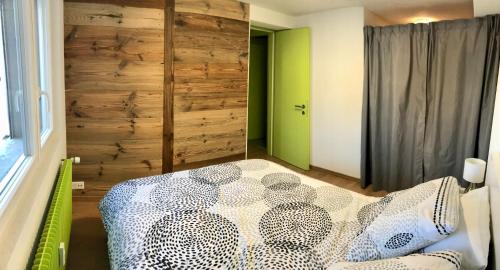 a bedroom with a bed and a wooden wall at Anzère, appartement cozy au coeur des Alpes in Anzère