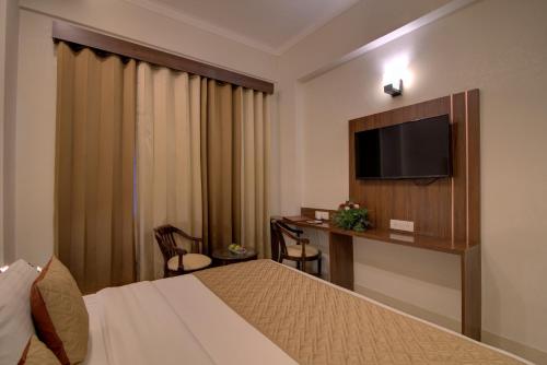 a hotel room with a bed and a flat screen tv at Comfort Inn Karnal in Taraori