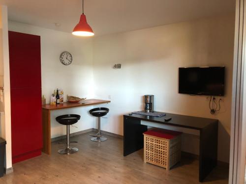 Cette chambre dispose d'un bureau, de deux tabourets de bar et d'une télévision. dans l'établissement Studio terrasse proche parc technologique, à Saint-Priest