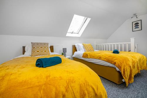 Impeccable 3-Bed House in Abbeywood في لندن: غرفة نوم بسريرين وبطانيات صفراء ونافذة