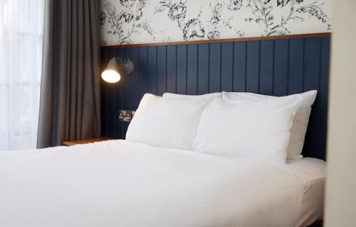 a bed with white pillows and a blue headboard at Swan Hotel by Greene King Inns in Alton