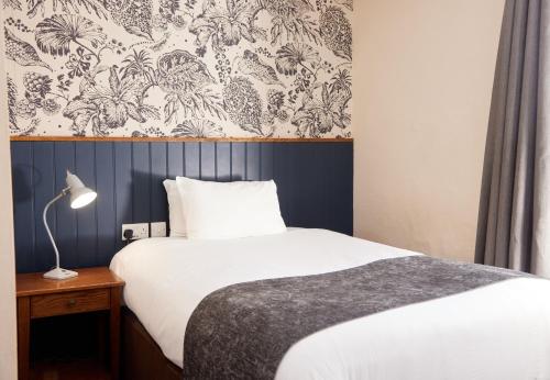 a bedroom with a bed and a wall with a wallpaper at Swan Hotel by Greene King Inns in Alton