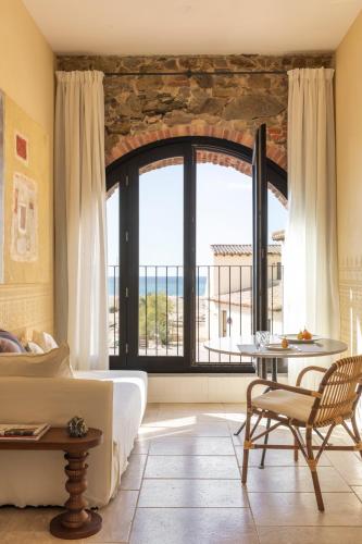 a bedroom with a bed and a table and a large window at Hotel Le Dune Piscinas in Ingurtosu